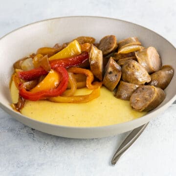 cheddar polenta in a bowl with sausage and peppers