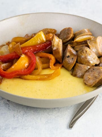 cheddar polenta in a bowl with sausage and peppers