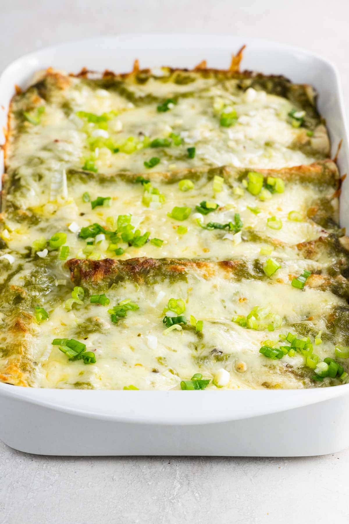 chicken and black bean enchiladas with green enchilada sauce in a pan