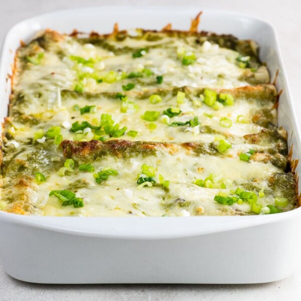 chicken and black bean enchiladas with green enchilada sauce in a pan
