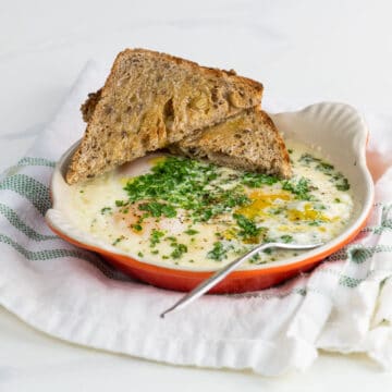 oeufs en cocotte (french baked eggs) with toast and a fork on a cloth napkin