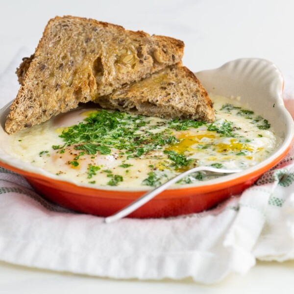 oeufs en cocotte (french baked eggs) with toast and a fork on a cloth napkin
