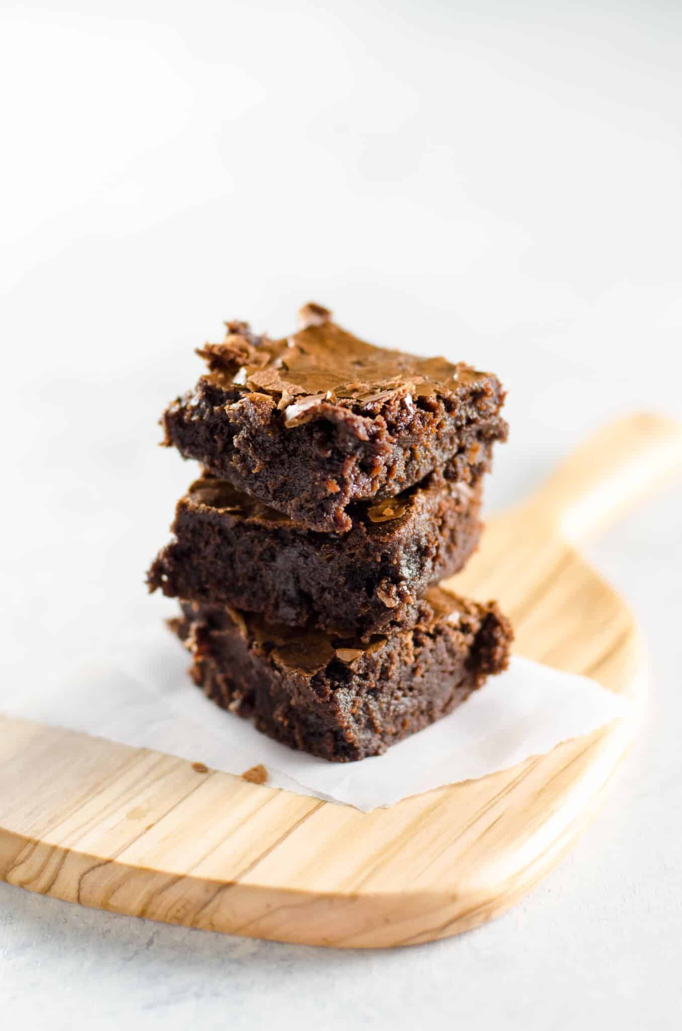 fudgy crinkly top brownies stacked on a cutting board