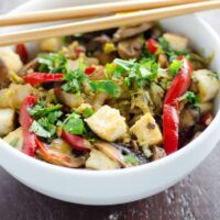 napa cabbage stir fry with salt and pepper tofu, mushrooms, and red bell pepper in a bowl with chopsticks