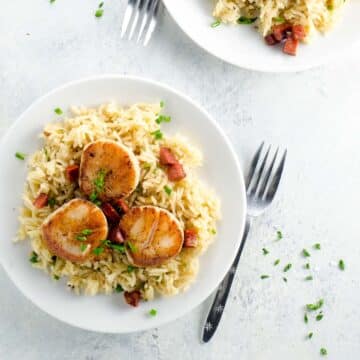 pan seared scallops with chorizo over basmati rice pilaf on plates with forks
