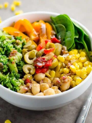 a veggie power bowl with chickpeas, broccoli, corn, spinach, peppers, olives, and balsamic vinaigrette