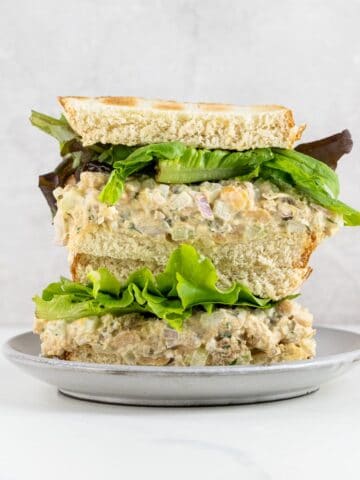 a chickpea tuna salad sandwich on toasted white bread with mixed greens