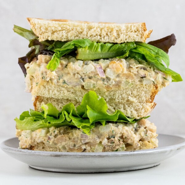 a chickpea tuna salad sandwich on toasted white bread with mixed greens