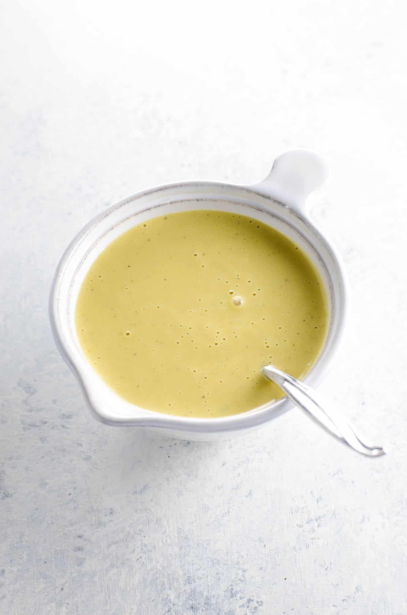 creamy lemon vinaigrette in a small white pitcher with a spoon