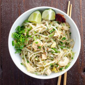 easy pad thai recipe in a bowl with chopsticks on a wooden background