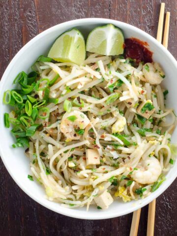 easy pad thai recipe in a bowl with chopsticks on a wooden background