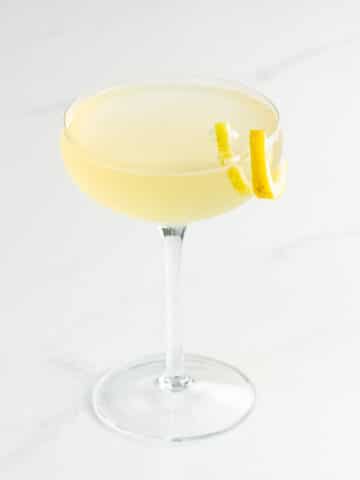 an elderflower french 75 with st germain in a coupe glass with a lemon twist