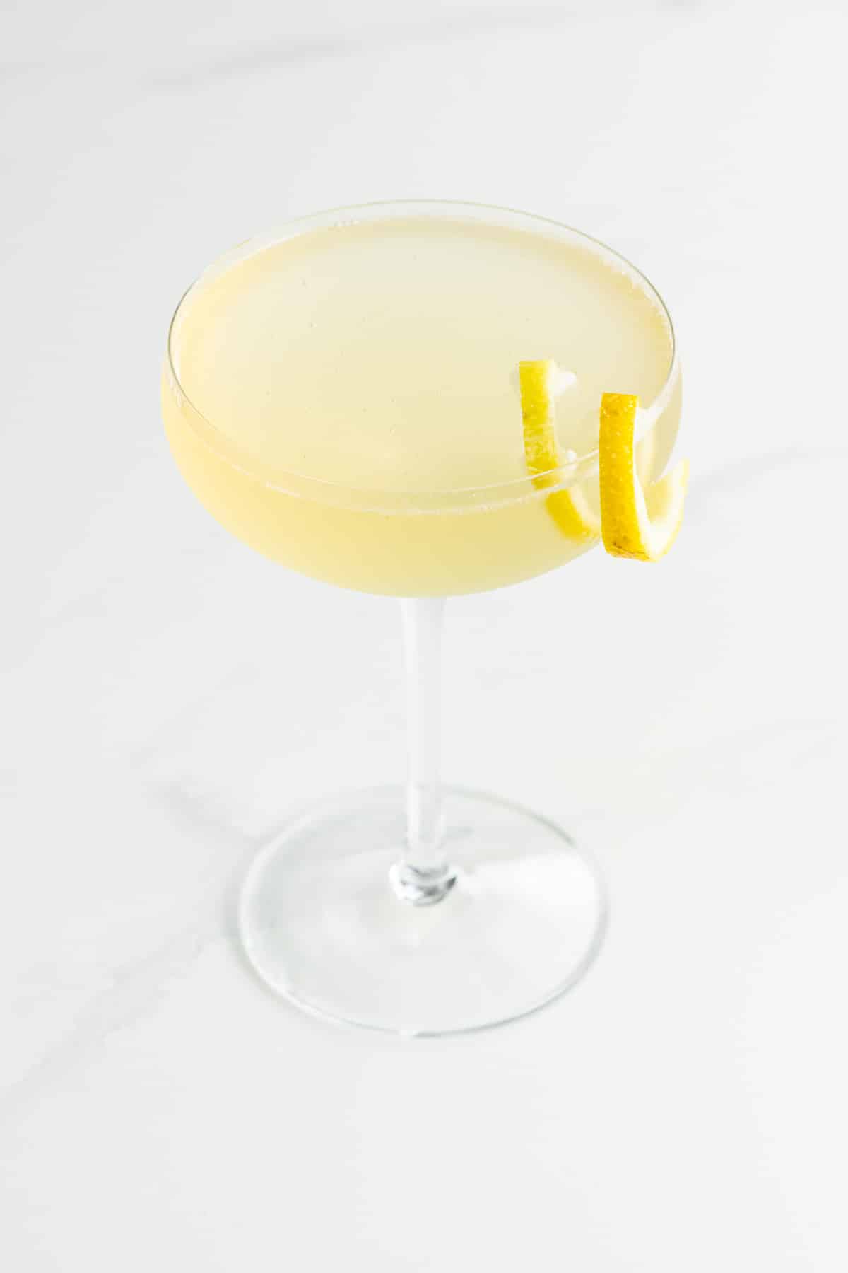 an elderflower french 75 with st germain in a coupe glass with a lemon twist