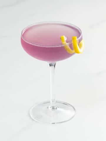 an empress 75 cocktail in a coupe glass with a lemon twist