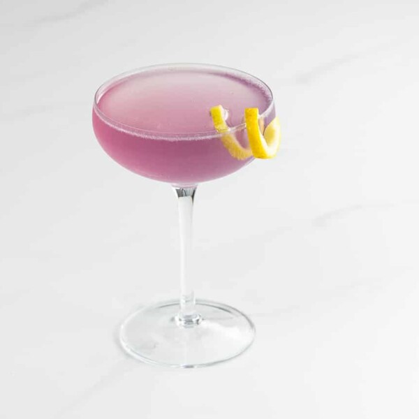 an empress 75 cocktail in a coupe glass with a lemon twist