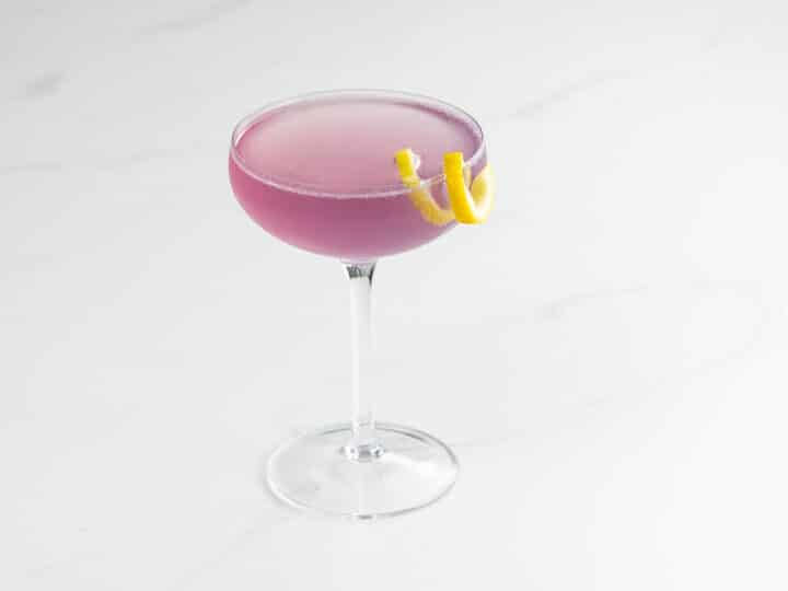 an empress 75 cocktail in a coupe glass with a lemon twist