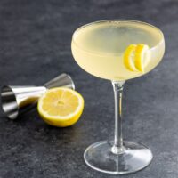 a french 76 cocktail in a coupe glass with a lemon twist