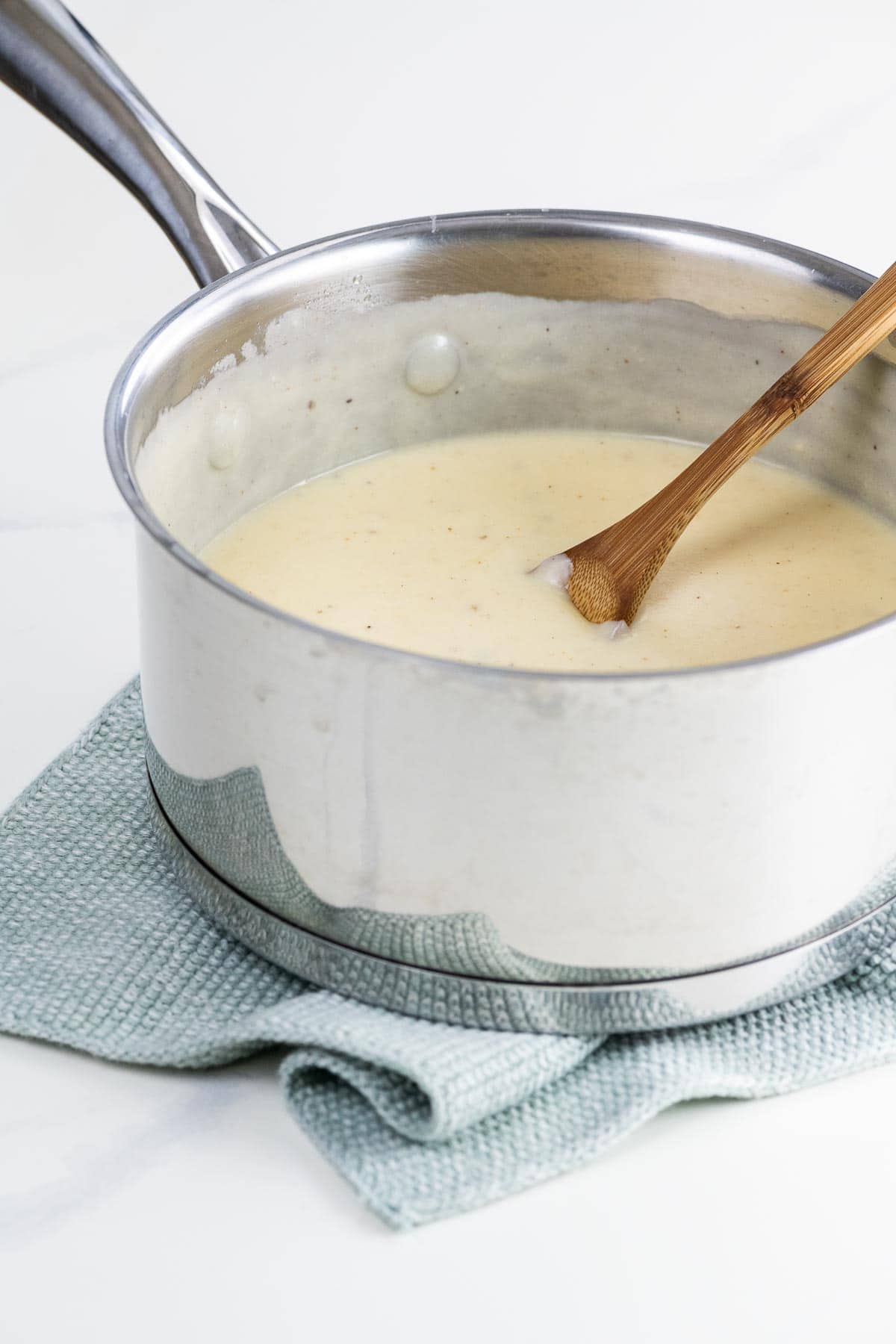 mornay sauce recipe in a pot with a wooden spoon