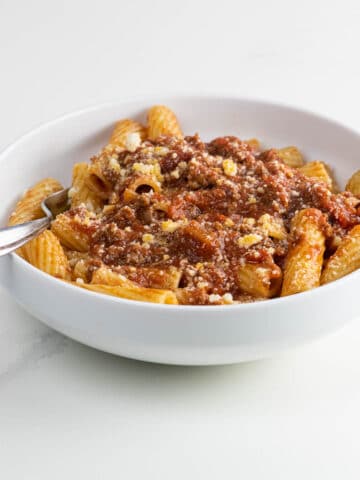rigatoni with meat sauce in a bowl with a fork