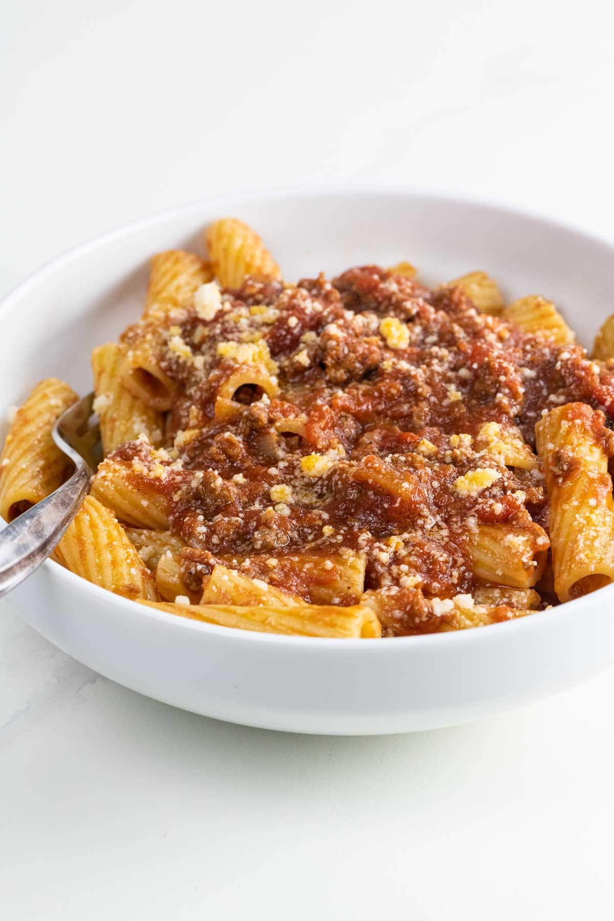 rigatoni with meat sauce in a bowl with a fork