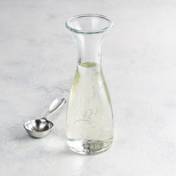 simple syrup for cake and cocktails in a small carafe with a measuring spoon