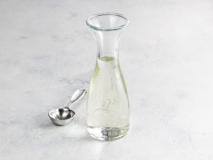 simple syrup for cake and cocktails in a small carafe with a measuring spoon