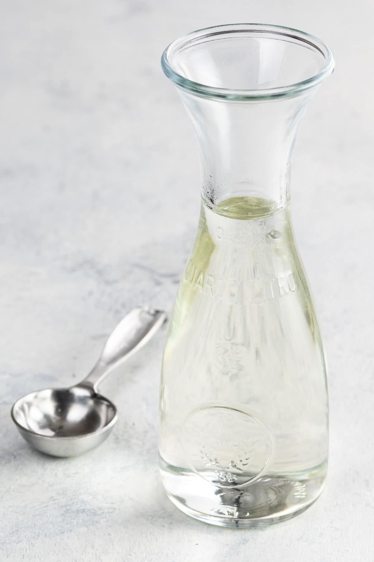 simple syrup for cake and cocktails in a small carafe with a measuring spoon