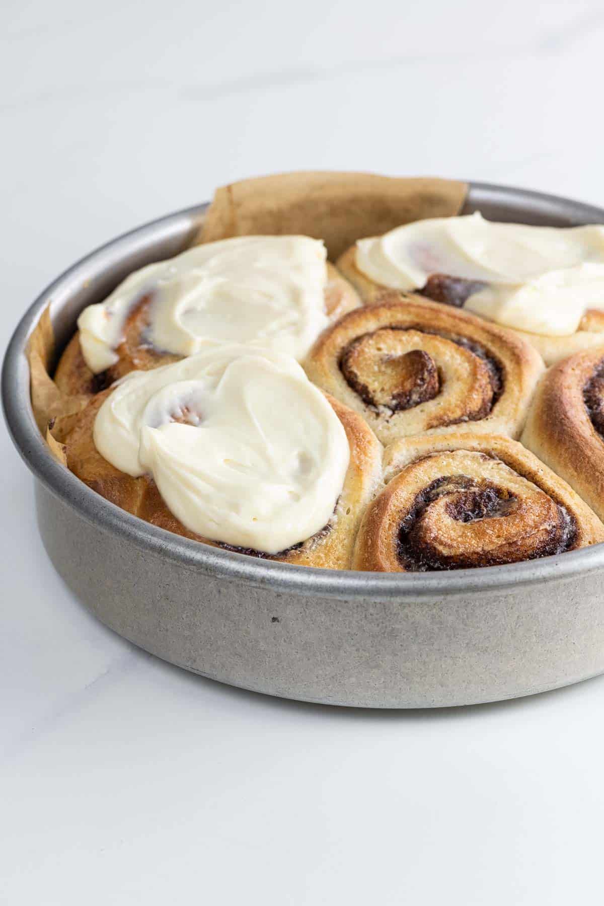 brioche cinnamon rolls with cream cheese icing in a pan