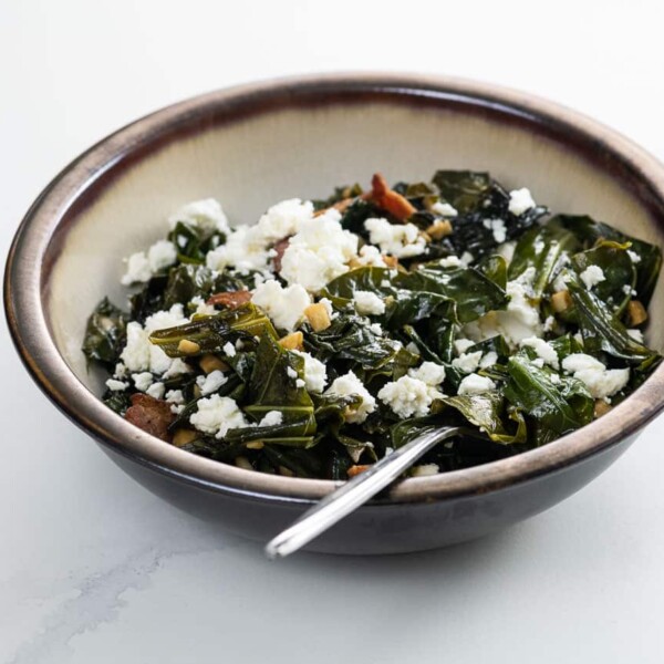 a bowl of cooking greens with bacon and feta
