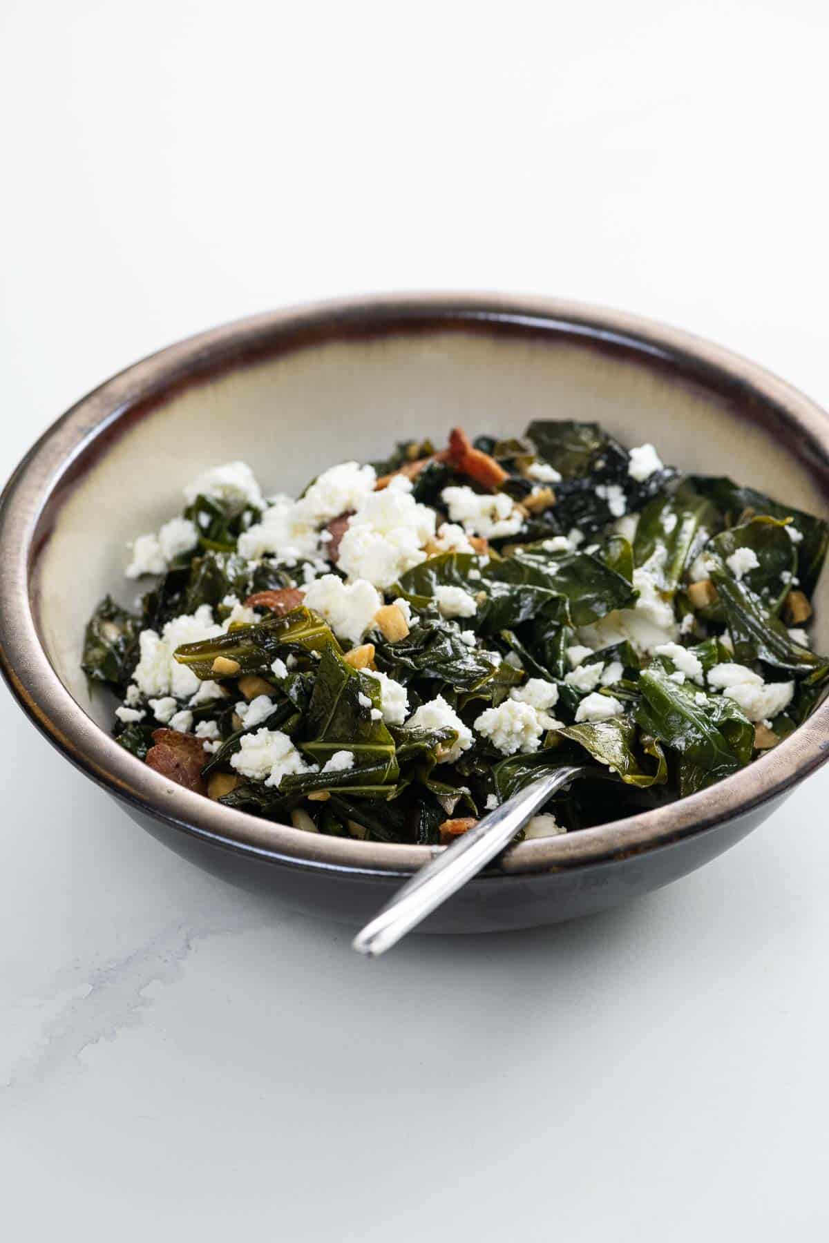 a bowl of cooking greens with bacon and feta