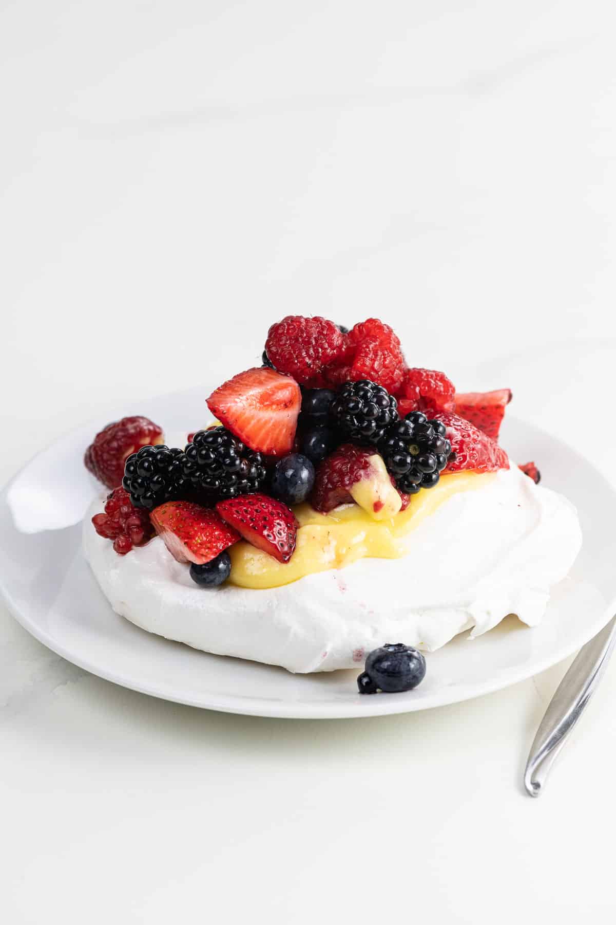 pavlova with lemon curd and berries on a plate with a fork