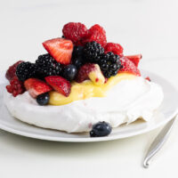 pavlova with lemon curd and berries on a plate with a fork