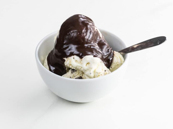 homemade chocolate sauce on ice cream in a bowl with a spoon