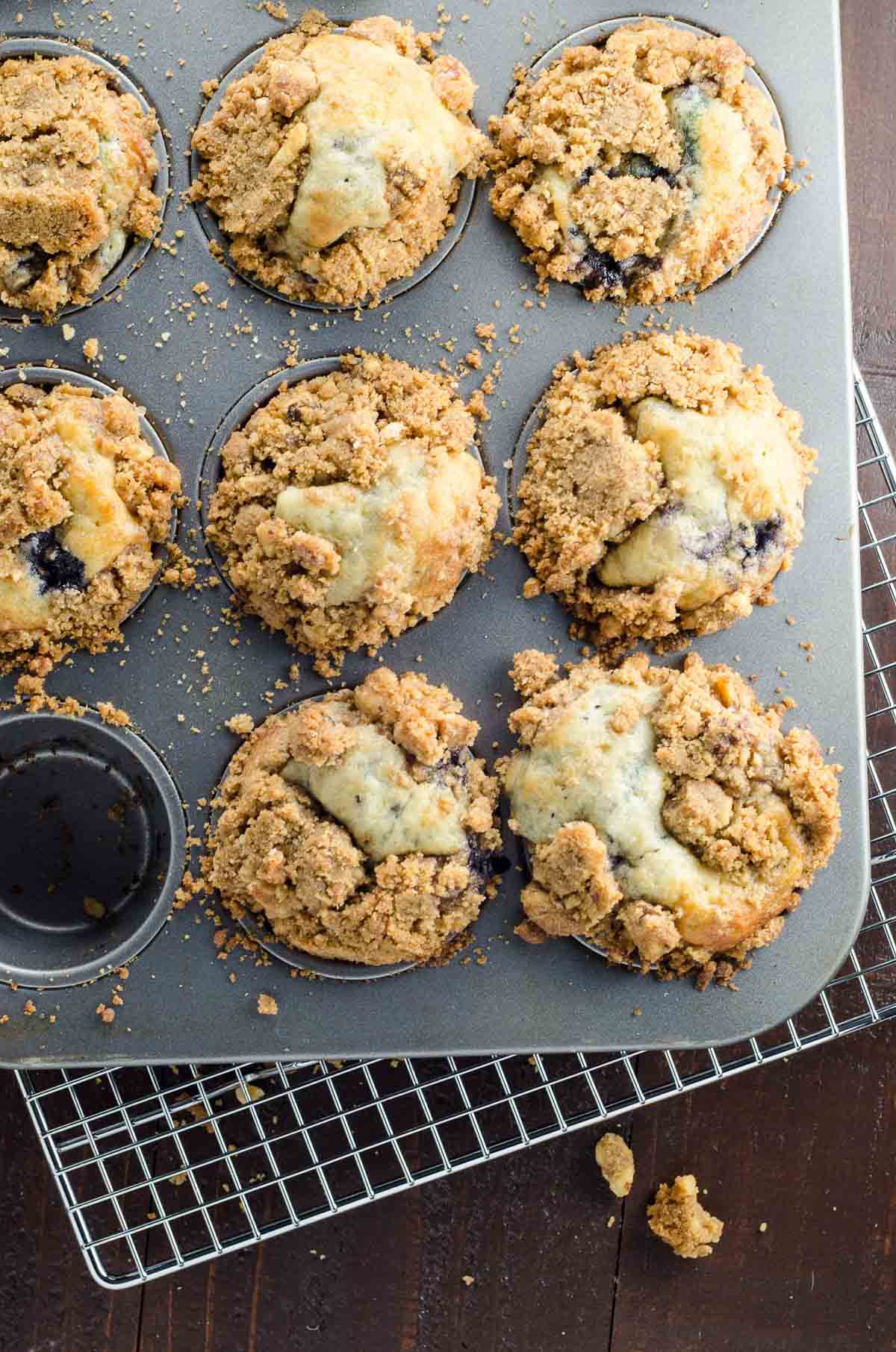 greek yogurt blueberry mufifins with streusel topping in a baking pan on a cooling rack