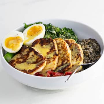 a halloumi bowl with lentils, broccolini, roasted red peppers, and a jammy egg