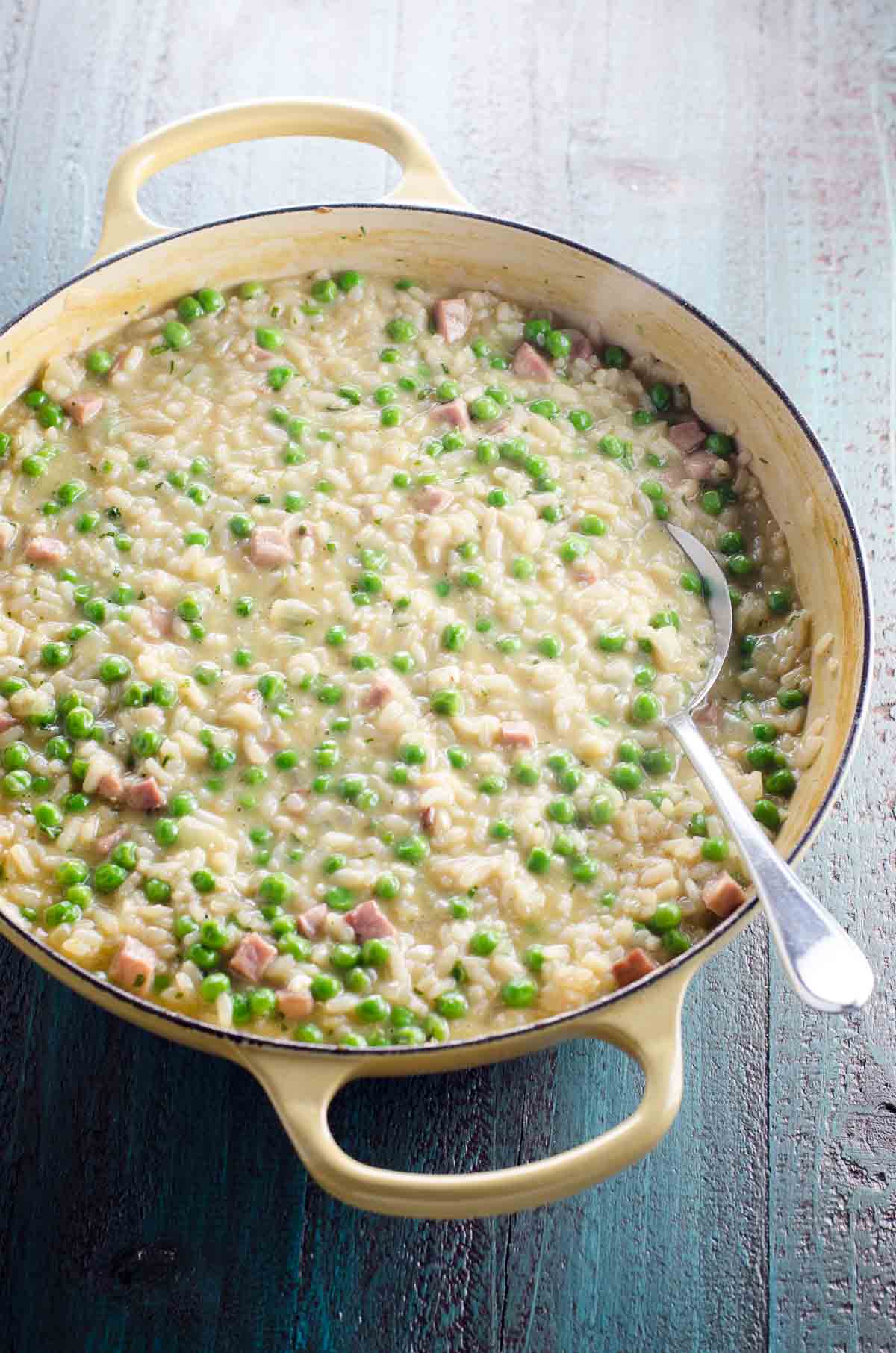 ham and pea risotto with feta and tarragon in a pan with a spoon