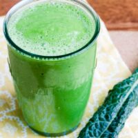 a glowing green smoothie and a piece of kale