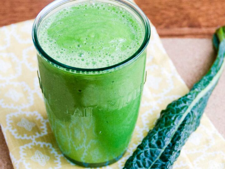 a glowing green smoothie and a piece of kale