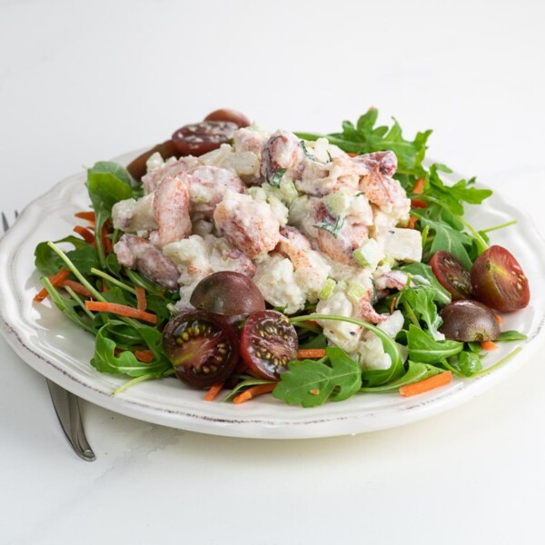 lobster salad on a plate with arugula, carrots, and tomato