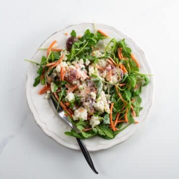 lobster salad on a plate with arugula, carrots, and tomato