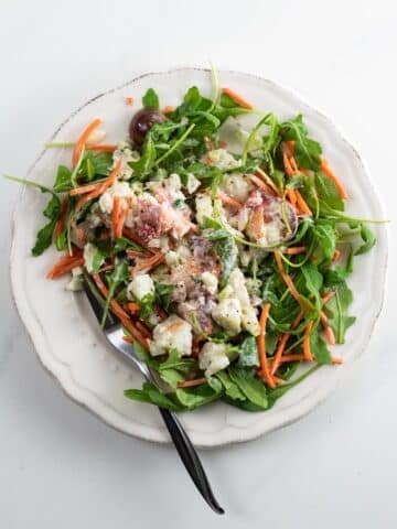lobster salad on a plate with arugula, carrots, and tomato