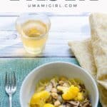 umami pasta with cauliflower, shiitakes, and chickpeas in a bowl with a glass of white wine