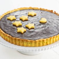 a bittersweet chocolate ganache tart with shortbread crust on a cake stand