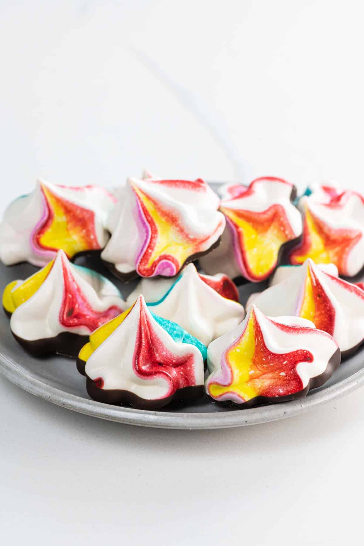 rainbow-colored chocolate meringue cookies on a plate