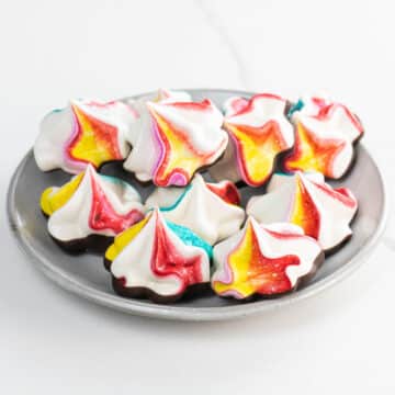 rainbow-colored chocolate meringue cookies on a plate