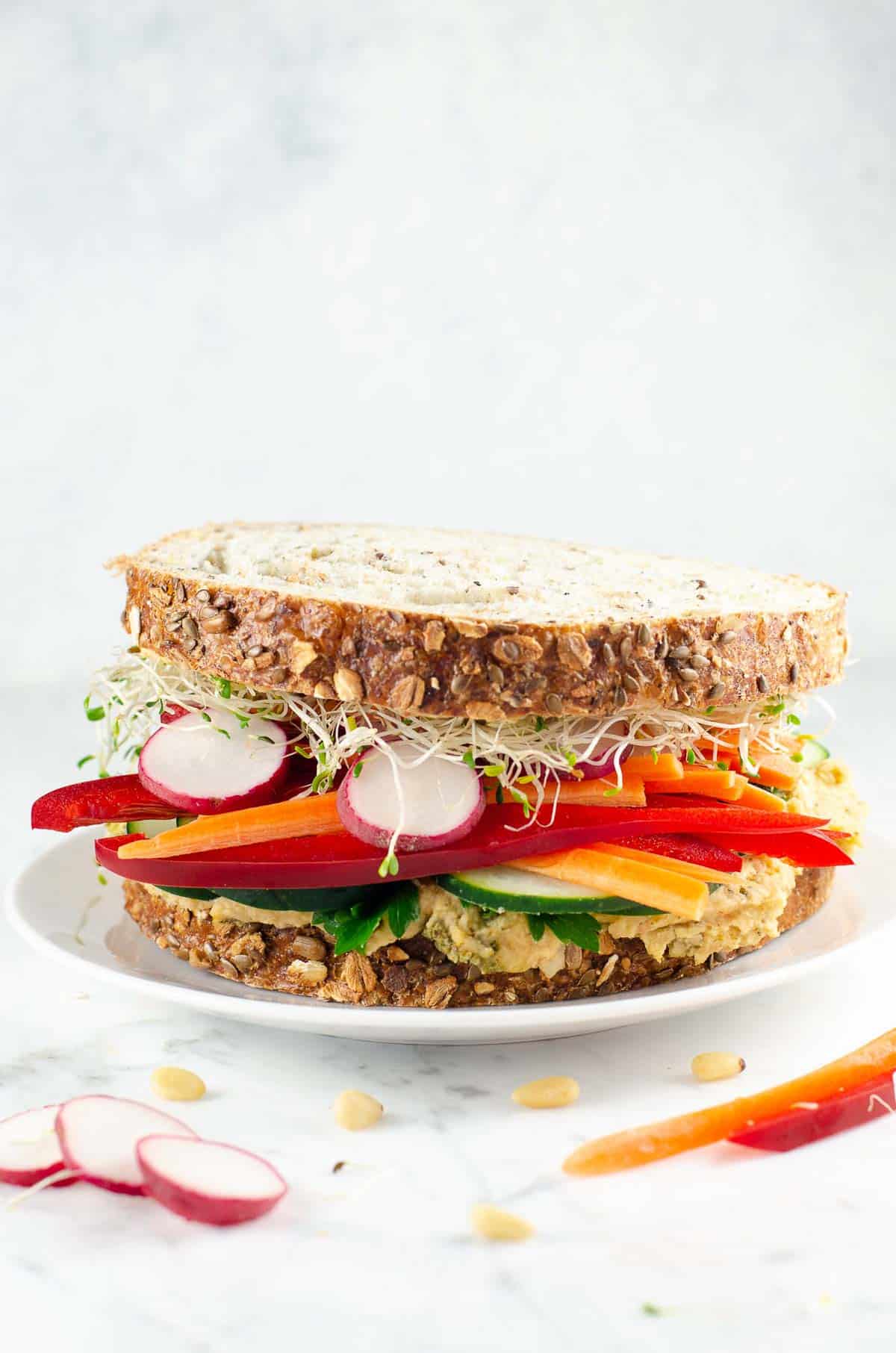 an epic veggie and white bean spread sandwich on a plate
