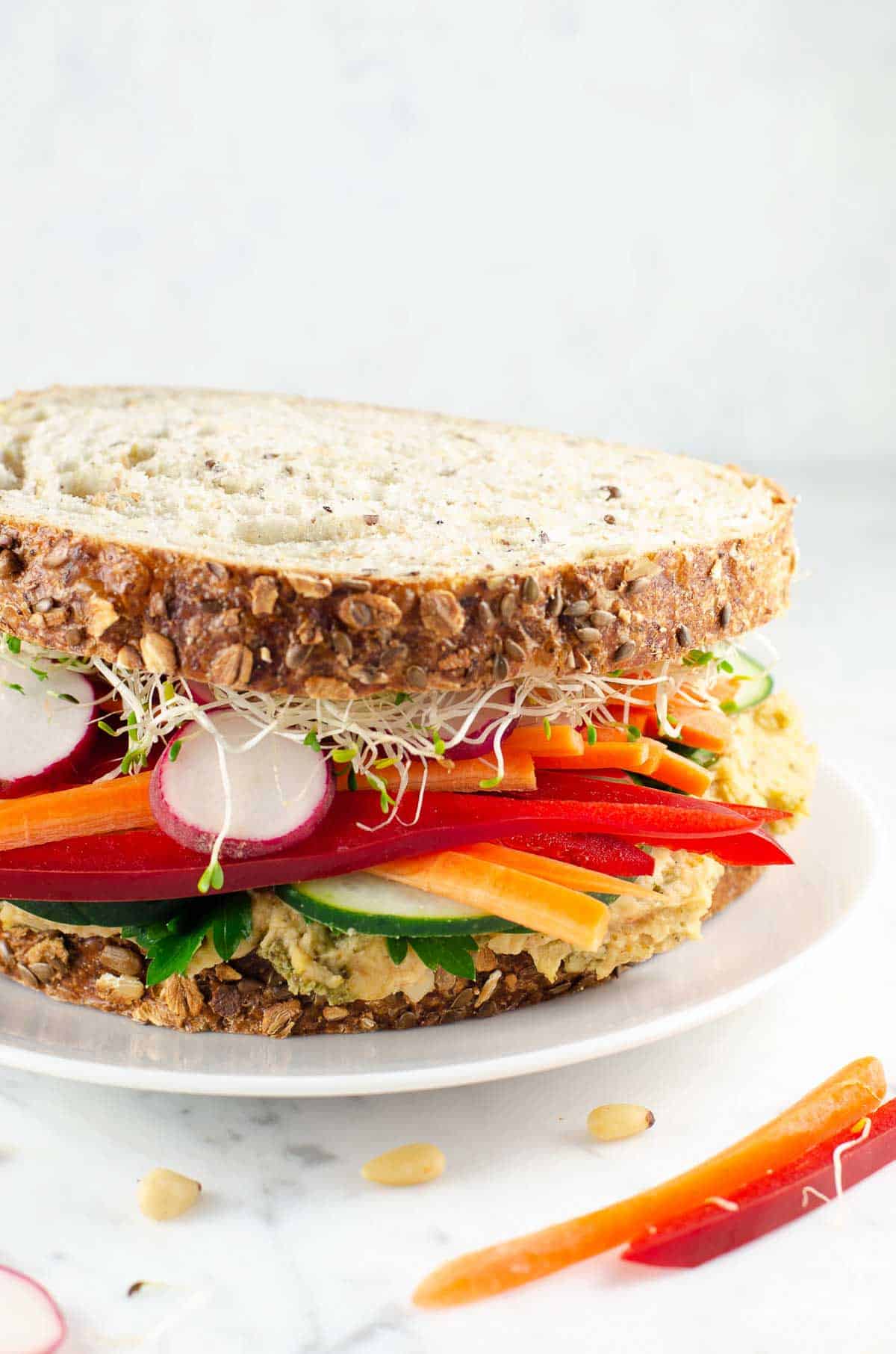 an epic veggie and white bean spread sandwich on a plate