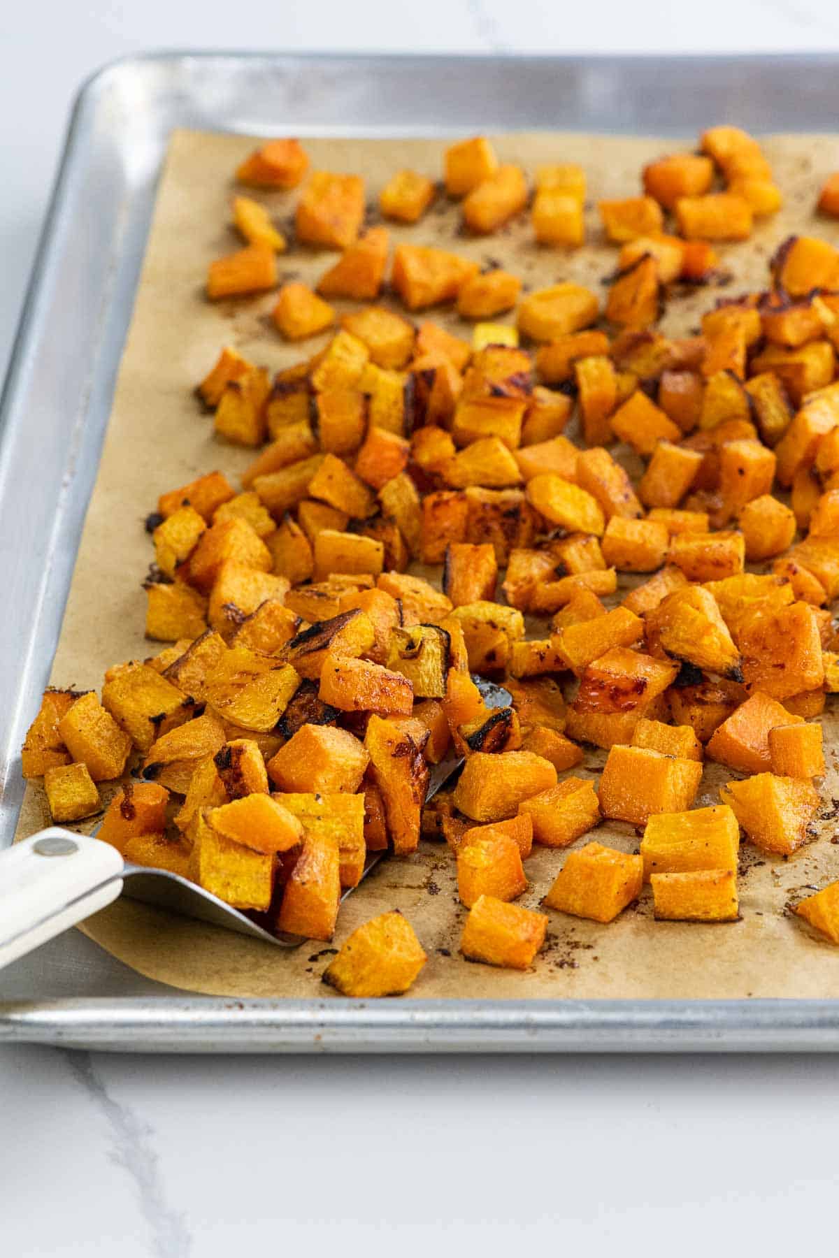 maple roasted butternut squash on a sheet pan with a spatula