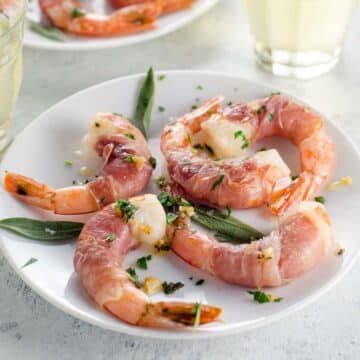 prosciutto wrapped shrimp on small plates with white wine