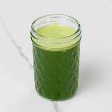 spinach juice with pineapple, green apple, and lime in a small glass